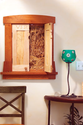 The kitchen is home to the straw bale house’s truth window, which, like a piece of art, opens to reveal the internal material of the walls.